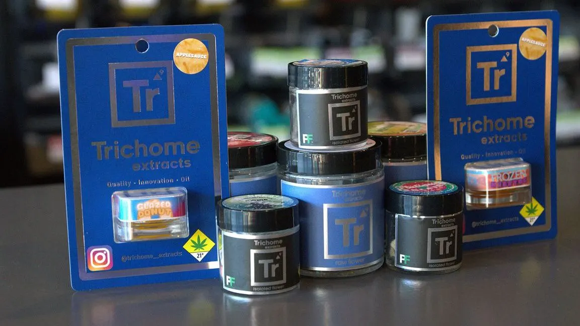 Trichome Extracts branded jars and packaging arranged on a surface